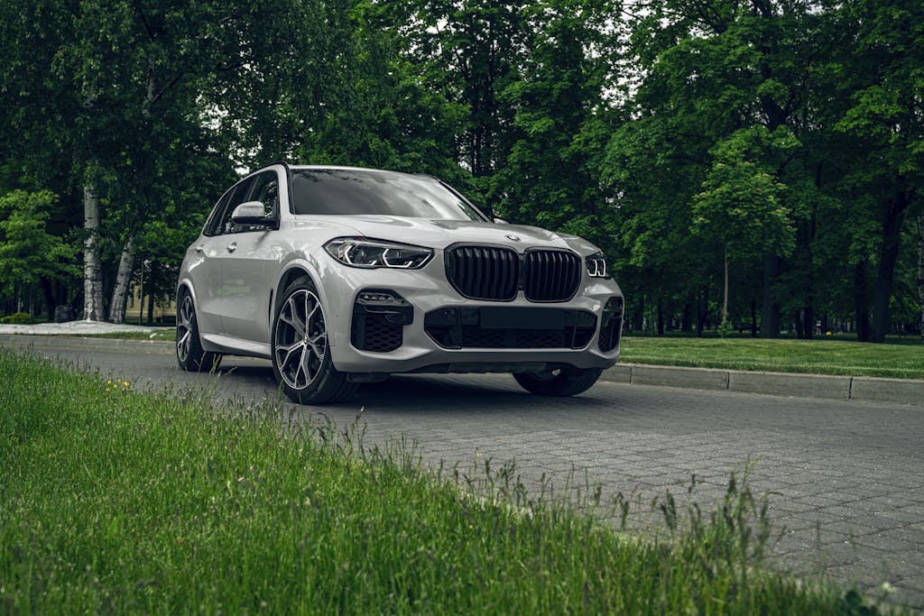 White BMW X5 SUV parked on a scenic road surrounded by lush greenery, showcasing elegance and style.